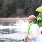 Courtney Pegus with a stuffed Kermit on his shoulders and other Polar Dip participants start off 2020 with a charge into the water at Auke Bay Recreation Area. (Ben Hohenstatt | Juneau Empire)
