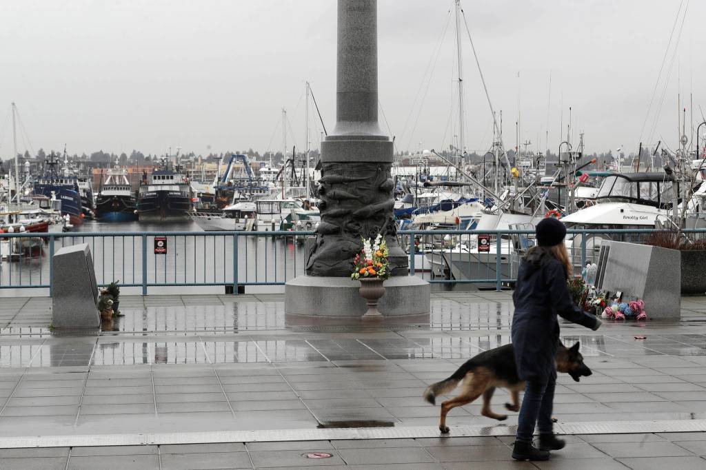 A pedestrian and a dog walk past the Seattle Fishermens Memorial, Thursday, Jan. 2, 2020, in Seattle. (AP Photo | Ted S. Warren)