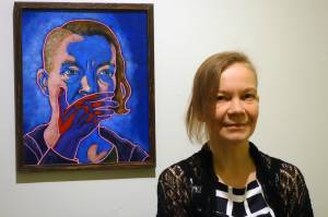 Inari Kylänen stands near her painting, Act of Doing Nothing is Still an Act II The Southern Border during an opening reception for the new exhibition A Nation of Immigrants Friday, Jan. 3, at the Juneau-Douglas City Museum. (Ben Hohenstatt | Capital City Weekly)