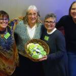 Marla Berg, organizing committee member for 100 Women Who Care Juneau; Kate Troll, who pitched the idea of donating to Renewable Juneau; Iola Young, organizing committee member for 100 Women Who Care Juneau; and Jane Lindsey, organizing committee member for 100 Women Who Care Juneau; smile with baskets filled with name tags and checks at the Hangar Ballroom, Thursday, Jan. 16, 2020. (Ben Hohenstatt | Juneau Empire)