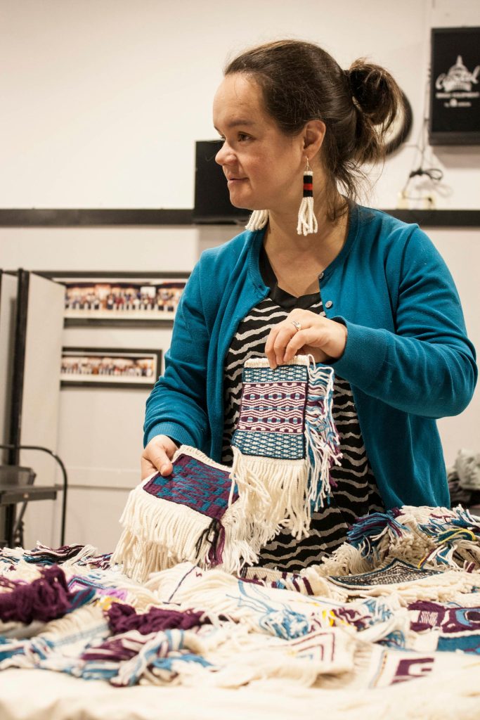 photos by Ben Hohenstatt | Capital City Weekly                                Lily Hope holds up patches that will be woven into the Giving Strength Robe, a Chilkat robe meant to honor survivors of domestic violence. The in-progress robe was present Sunday at a work session that featured a dozen weavers.