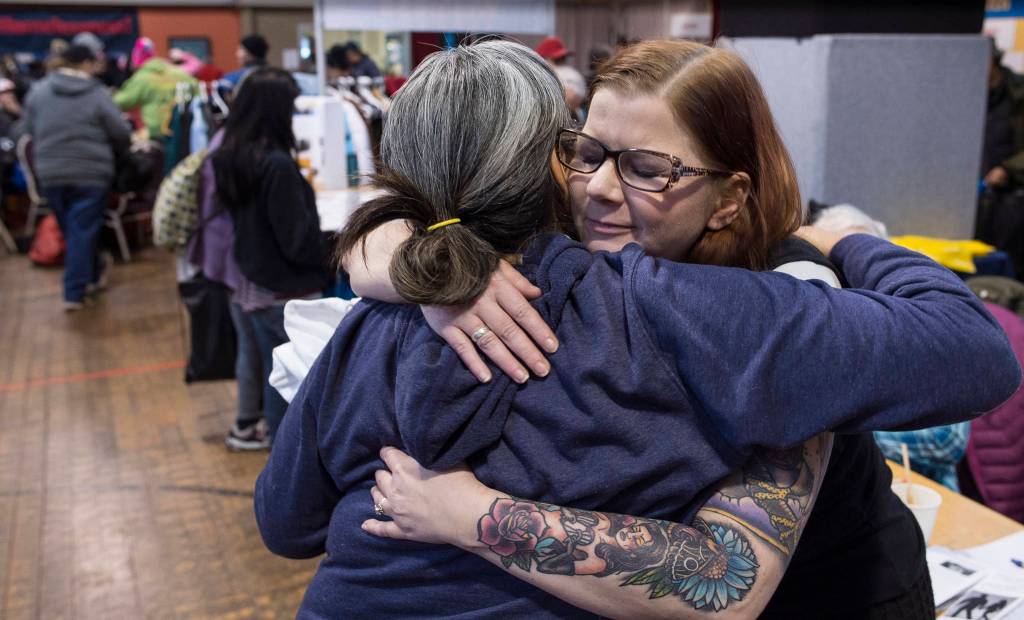 Kimberly Sumner, right, of AWARE, gives a hug to an attendee of the Juneau Coalition on Housing & Homelessness 7th annual Project Homeless Connect in the Juneau Arts & Culture Center on Wednesday, Jan. 24, 2018. ( Michael Penn | Juneau Empire File)