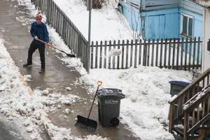 A man shovels snow near the state capitol as rising temperatures turn the roads to slush, Jan. 22, 2020. (Michael S. Lockett | Juneau Empire)