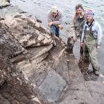 Kevin May | UA Museum of the North                                Gene Primaky, Jim Baichtal and Patrick Druckenmiller stand in rising tidewater after the last of the two blocks was removed. Minutes later, the tide submerged the excavation site.