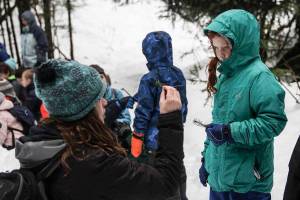 Discovery Southeast education coordinator Kelly Sorensen talks to a student from Harborview Elementary School about what feeds on the trees during a nature hike near the Mendenhall Glacier Visitor Center on Feb. 20, 2020. (Michael S. Lockett | Juneau Empire)