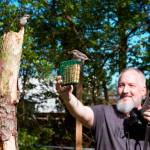 In this photo taken April 27, 2020, provided by Michael Kopack III, amateur bird watcher Michael Kopack Jr. holds his camera in the background while two nuthatches land nearby in Angier, N Kopack has gotten deeply involved in bird-watching during the coronavirus pandemic and put up a birdhouse for the first time this spring. (Michael Kopack III via AP)