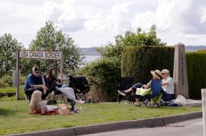 Members of the de Rham family from the U.S. and Canada visit at the border between the countries in Peace Arch Park, in Blaine, Wash. With the border closed to nonessential travel amid the global pandemic, families and couples across the continent have found themselves cut off from loved ones on the other side. But the recent reopening of Peace Arch Park, which spans from Blaine into Surrey, British Columbia, at the far western end of the 3,987-mile contiguous border, has given at least a few separated parents, siblings, lovers and friends a rare chance for some better-than-Skype visits. (AP Photo/Elaine Thompson)