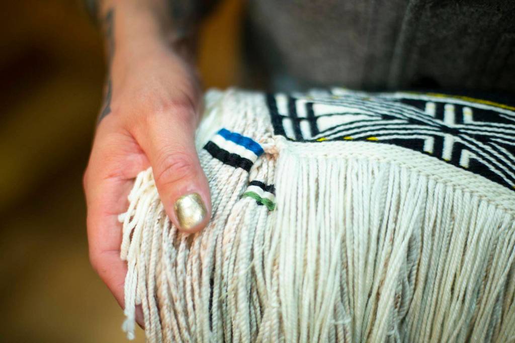 Ricky Tagaban shows the woven artist signatures on the robe he and Lily Hope collaborated to weave at its first dance ceremony at the Sealaska Heritage Institute on Monday, June 22, 2020. (Courtesy photo | Annie Bartholomew)