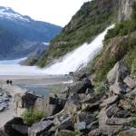People walk near Nugget Falls Thursday, July 30, 2020. A flood warning is in effect for Mendenhall Lake and Mendenhall River through 10 a.m. Saturday, Aug. 1, 2020. As water levels rise, recreation sites near the glacier may be hazardous or inaccessible. (Ben Hohenstatt / Juneau Empire)