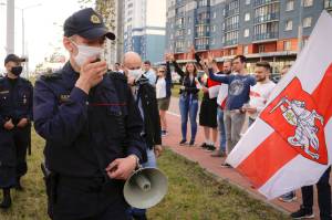 Supporters of the opposition flash victory signs as a police patrol walks by warning people that the protest is not authorized and asking them to leave in Minsk, Belarus, Friday, Aug. 21, 2020. Belarus authorities have detained a leader of striking factory workers and threatened protesters with criminal charges in a bid to stem massive protests challenging the extension of the 26-year rule of the countrys authoritarian president Alexander Lukashenko, who accused the U.S. of fomenting the unrest and vowed to see a quick end to protests. (AP Photo / Sergei Grits)