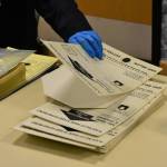 Poll workers at the Douglas Community Building show the coverings used to keep completed ballots covered and secret which this year are also being used to reduce contact with the ballot itself. The laminated coverings are sanitized after each use, part of the extra health precautions in place for the 2020 Primary Election on Tuesday, Aug. 18, 2020. (Peter Segall / Juneau Empire)