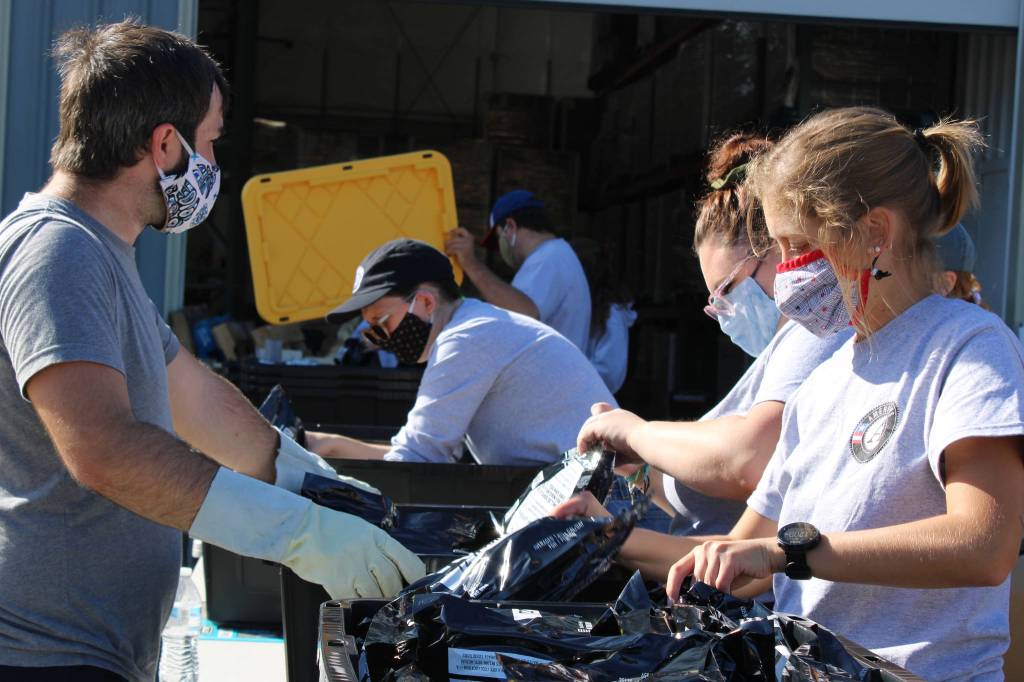 AmeriCorps volunteers place three-day supplies of emergency rations into a container on Sept. 11, 2020. They had packed over 8,500 such supplies by 12:30 p.m.. (Ben Hohenstatt / Juneau Empire)