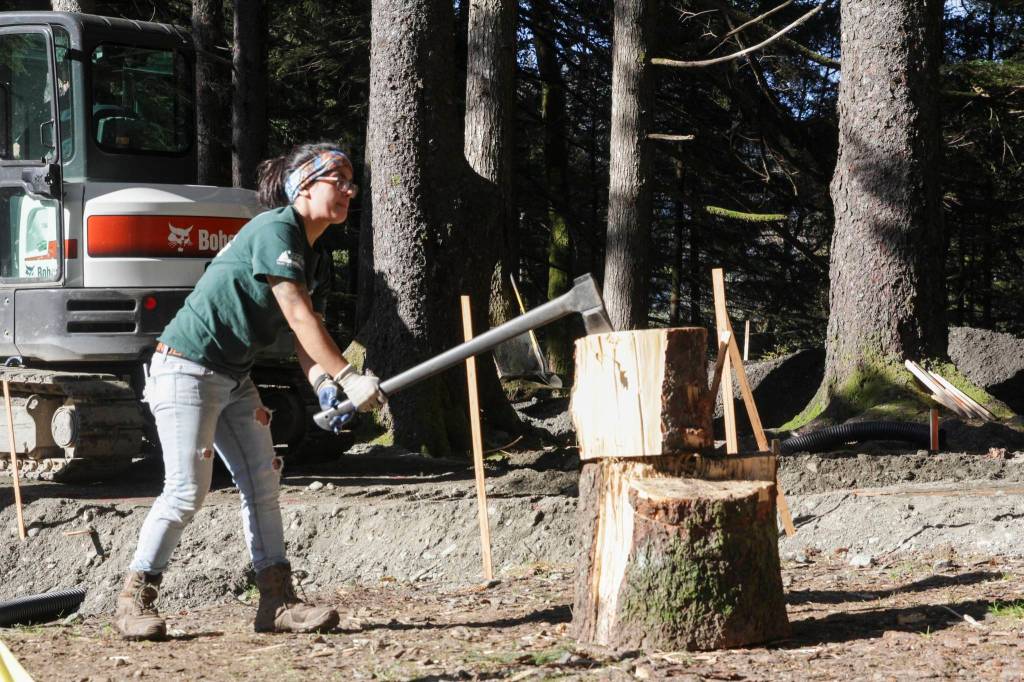 Whitney Parks, a member of Juneaus COVID Conservation Corps, chops logs Wednesday as she helps with the construction of the new pump track at Cope Park.