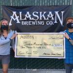 Brian Murphy, right, ran 50 miles to raise money for Juneau Mountain Rescue, a wilderness-rescue nonprofit. Jackie Ebert, left, is shown receiving the novelty check for the $3,250 raised on Murphys Aug. 30 run on behalf of the JMR. (Courtesy Photo / Andy Kline)