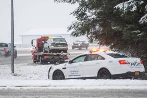 The Juneau Police Department Community Service Officer waits as a vehicle is pulled out of the ditch at the intersection of Egan and Yandukin Drives near Fred Meyer on Thursday, Dec. 13, 2018. The Department of Transportation and Public Facilities has announced five proposed alternatives to better manage traffic at the intersection. (Michael Penn | Juneau Empire File)