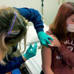 In this photo provided by Cincinnati Childrens Hospital Medical Center, clinical research coordinator Tammy Lewis-McCauley administers an injection to Katelyn Evans, a trial participant, as part of the hospitals clinical trial of Pfizers COVID-19 vaccine at Cincinnati Childrens Hospital Medical Center on Wednesday, Oct. 14, 2020. (Cincinnati Childrens Hospital Medical Center via AP)