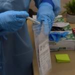 Emergency worker Melanie Chavez takes a COVID-19 test sample at the Juneau International Airport screening site on Monday, Oct. 12, 2020. City officials said Tuesday contact tracers are behind in tracking down positive COVID-19 cases. (Peter Segall / Juneau Empire)