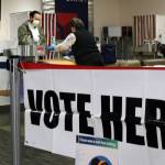 Nicolas Blanco fills out paperwork ahead of voting absentee at Juneau International Airport on Election Day. Blanco recently moved to Juneau from North Carolina, so cast an absentee ballot. He was assisted by election officials Carol Whelan, right, and Lala Levale, not pictured. (Ben Hohenstatt / Juneau Empire)