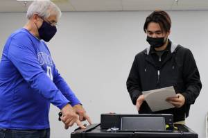 Election official Steve Lewis directs voter Patrick Endozo, who attempts to feed his completed ballot into a scanning machine at a polling place inside Nugget Mall on Election Day. Election officials said shortly before 5 p.m. that about 150 more people had voted at the polling place than voted there in the state's August primary. (Ben Hohenstatt / Juneau Empire)