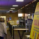 Passengers at the Juneau International Airport make their way past signage notifying the public about the states travel restrictions on Monday, Nov. 15, 2020. Gov. Mike Dunleavy issued a new emergency declaration which took effect Monday, which outlined a number of travel guidelines for both in-state and out-of-state travel. (Peter Segall / Juneau Empire)