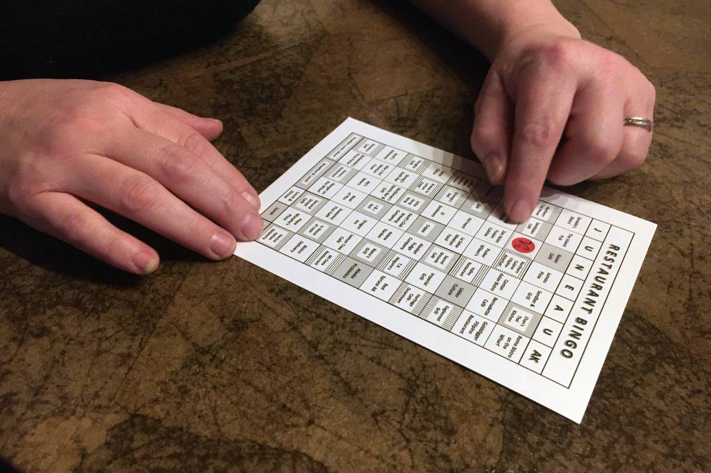 Venietia V Santana, owner of Vs Cellar Door, fills in a Juneau Restaurant Bingo card on Dec. 4, 2020. Vs Cellar Door is one of 63 participating eateries. (MIchael S. Lockett / Juneau Empire)