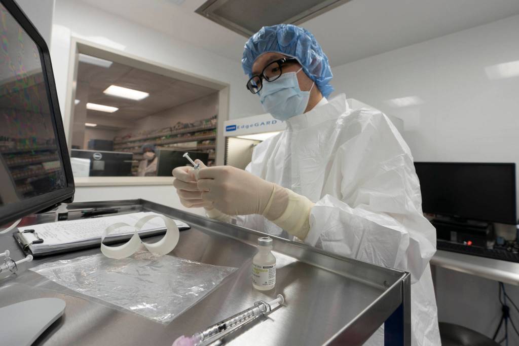 A pharmacist labels syringes in a clean room where doses of COVID-19 vaccines will be handled, Wednesday, Dec. 9, 2020, at Mount Sinai Queens hospital in New York. The hospital expects to receive doses once a vaccine gets the emergency green light by U.S. regulators. (AP Photo / Mark Lennihan)