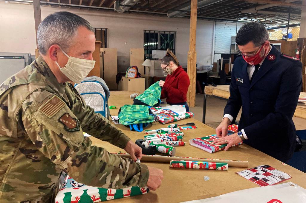 Chief Master Sgt. Winfield Hinkley Jr., Command Senior Enlisted Leader of the Alaska National Guard, left, Makayla Hikley, middle, and Maj. John Brackenbury, divisional commander with the Salvation Army, Alaska Division, wrap gifts in Anchorage, Alaska, that will be sent to children in three rural Alaska villages, on Nov. 17, 2020. The Alaska National Guard and the Salvation Army were able to provide and deliver gifts for the programs 65th year, but had to scale back distribution parties that are normally held in the villages because of COVID-19. (AP Photo / Mark Thiessen)