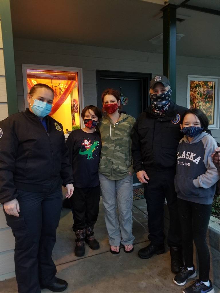 Department of Corrections Officer Ed Irizarry and TSA Officer Brenda Irizarry, along with their daughter, Bridget, deliver presents to April Nestler and her son, Owen as part of the Alaska Police Officers Association annual Shop with a Cop event. (Courtesy photo / APOA)