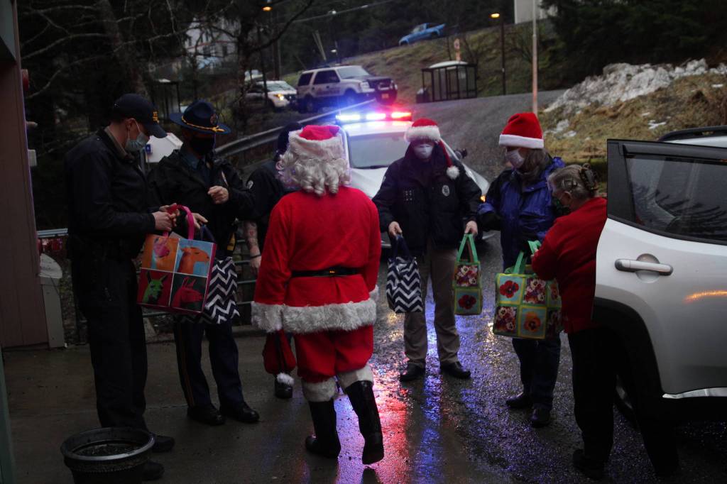 Law enforcement officers and volunteers deliver presents to families at the AWARE shelter on Dec. 23, 2020 as part of the Alaska Police Officers Association annual Shop with a Cop event. (Michael S. Lockett / Juneau Empire)