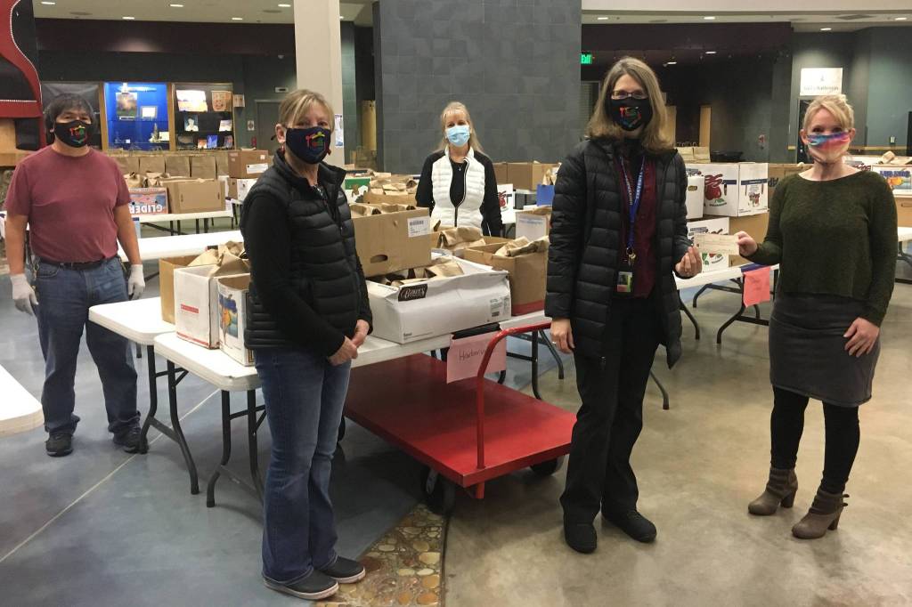 Photos by Michael S. Lockett / Juneau Empire
Members of the Juneau Education Support Staff union pose for a photo in front of meals being prepared for kids in Juneau as Catherine Pusich, second from right, hands a check from the union to Adrianne Schwartz to clear all money owed for school meals at Thunder Mountain High School on Dec. 21.