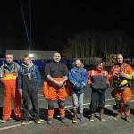 An MH-60 Jayhawk helicopter crew from Air Station Sitka pose with the family they rescued about an hour earlier from Yamani Islets, Dec. 25, 2020. The aircrew hoisted all four family members to safety after their boat capsized. (Courtesy Photo / Coast Guard Air Station Sitka)