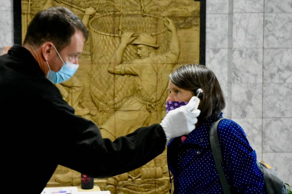 Rep. Jennifer Johnston, R-Anchorage, gets her temperature taken as she enters the Alaska State Capitol on Monday, May 18, 2020. New policies will require all staff and legislators to wear masks in chambers. (Peter Segall / Juneau Empire File)