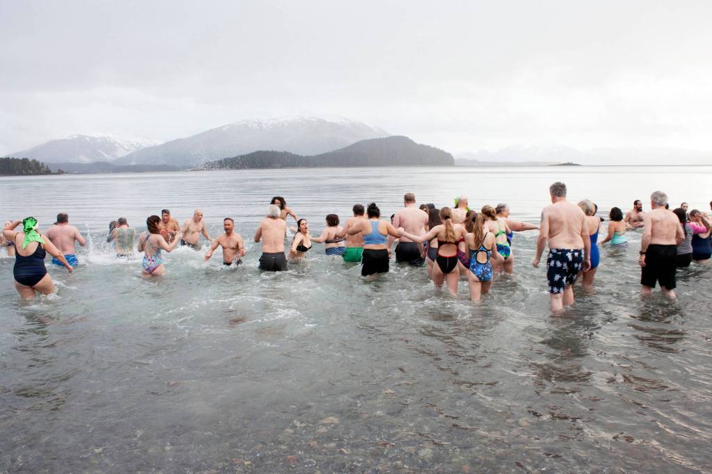 Polar Bear Dip participants make a mad dash Wednesday, Jan. 1, 2020, into the cold water at Auke Bay Recreation Area. This years dip is cancelled due to pandemic concerns. (Ben Hohenstatt / Juneau Empire File)