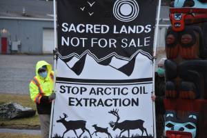 Tom Wagner, left and Bob Schroeder hold up a banner protesting resource extraction in the Arctic at Saviko Park on Wednesday, Jan. 6, 2020. Members of environmental groups 350Juneau and Native Movement held a traveling demonstration Wednesday, taking the banner to several locations in Juneau, including the state capitol. (Peter Segall / Juneau Empire)