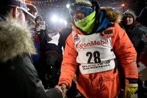 Joar Leifseth Ulsom, right, wearing a bib with ExxonMobil lettering on it, congratulates Peter Kaiser on his win in the Iditarod Trail Sled Dog Race in Nome, Alaska. The worlds most famous sled dog race has lost another major sponsor as the Iditarod prepares for a scaled-back version of this years race because of the pandemic, officials said Thursday, Jan. 21, 2021. ExxonMobil confirmed to The Associated Press that the oil giant will drop its sponsorship of the race. (Marc Lester / Anchorage Daily News)
