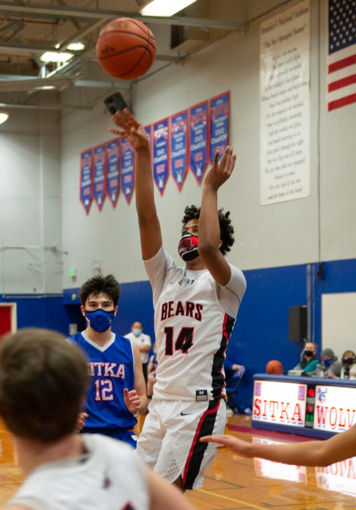 Juneau-Douglas High School Yadaa.at Kalé player Malakai Nichols shoots for three as Sitkas Shane Webb looks on Thursday night at Sitka High. (Sitka Sentinel / James Poulson)