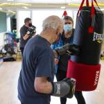 Steve Wolf strikes a punching bag as his wife Bev Ingram holds it during a boxing class designed to help fight back against the symptoms Parkinsons disease through a specific regimen at Pavitt Health and Fitness on March. 2, 2021. (Michael S. Lockett / Juneau Empire)