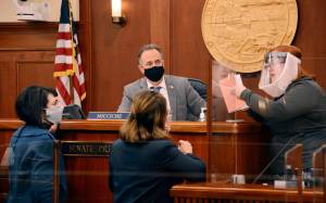 Alaska Senate Secretary Liz Clark, right, holds a copy of the Alaska Legislature's uniform rules as she talks to Sen. Lora Reinbold, R-Eagle River, center, while Senate President Peter Micciche, R-Soldotna and Senate Majority Leader Shelley Hughes, R-Palmer, in the Alaska State Capitol in Juneau, Alaska, Wednesday, March 10, 2021. Reinbold was excluded from most spaces in the Alaska State Capitol until she follows the Legislature's anti-COVID policies. (James Brooks / Anchorage Daily News via AP, Pool)