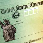 FILE - This May 8, 2008, file photo shows blank checks on an idle press at the Philadelphia Regional Financial Center, which disburses payments on behalf of federal agencies in Philadelphia. Officials at the Treasury Department and Internal Revenue Service said Friday, March 12, 2021 that processing the new round of stimulus payments has already begun, with the aim of having the first payments start showing up in bank accounts this weekend. (AP Photo/Matt Rourke, File)