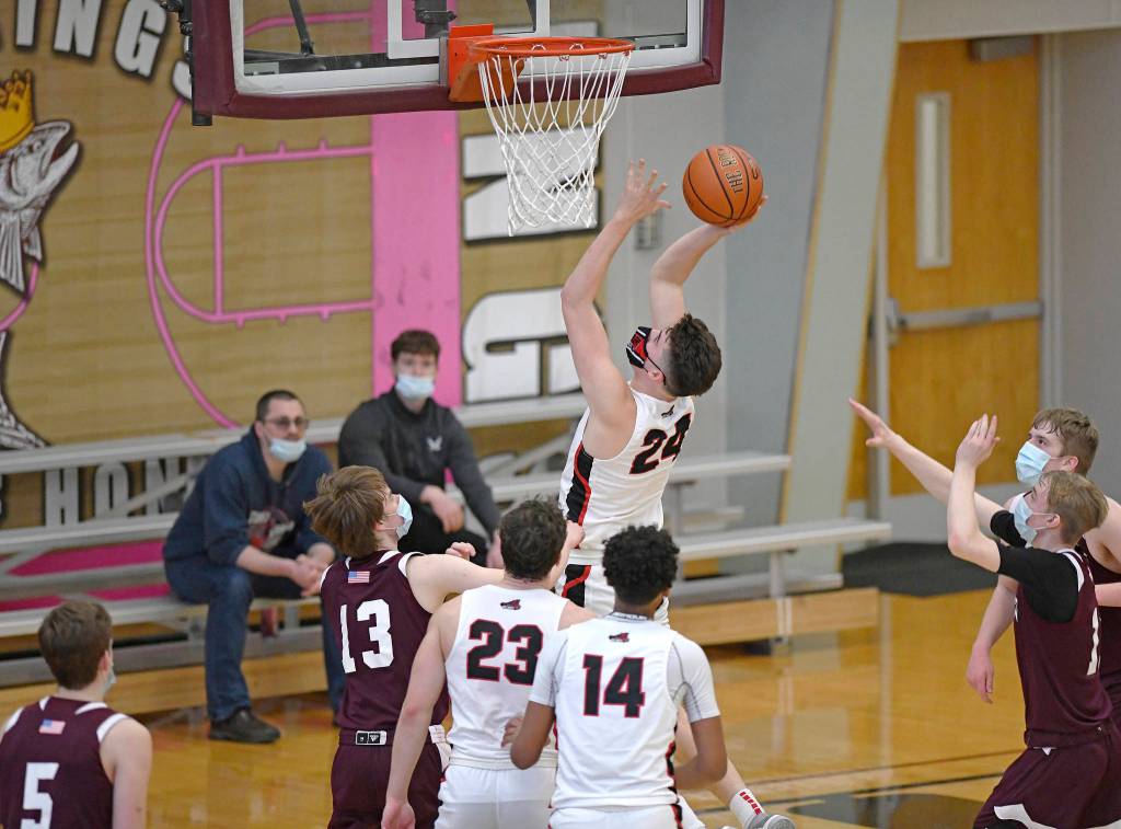 Juneau-Douglas High School Yadaa.at Kalé senior Garrett Bryant shoots from under the basket against Ketchikan High School senior Joshua Gentry (13) during the second half in the boys varsity Region V basketball championship at Clarke Cochrane Gymnasium on Saturday, March 20, 2021. JDHS won 87-68. (Dustin Safranek / Ketchikan Daily News)