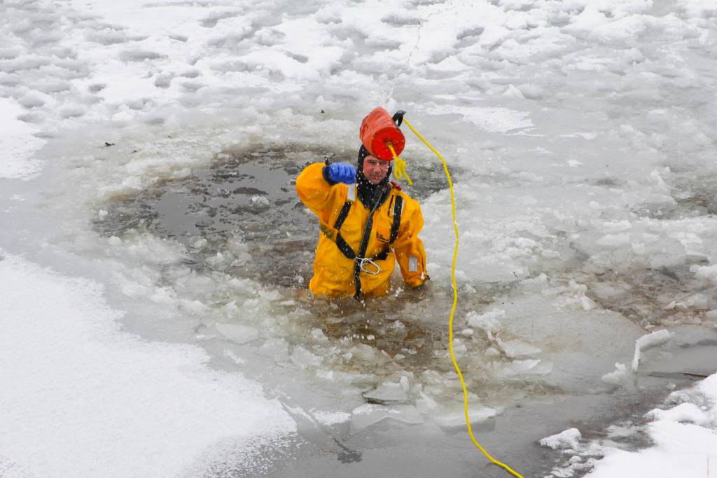 Capt. Jayme Johns, head of the Capital City Fire/Rescues water rescue team, chucks a rope bag back to shore during CCFRs annual ice rescue training at Twin Lakes on April 7, 2021. (Michael S. Lockett / Juneau Empire)