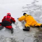 Capt. Jayme Johns, in yellow, head of the Capital City Fire/Rescues water rescue team, shows firefighter Liam Van Sickle, left, how to safely cross treacherous ice during CCFRs annual ice rescue training at Twin Lakes on April 7, 2021. (Michael S. Lockett / Juneau Empire)
