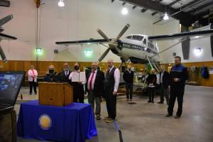 State lawmakers including Juneau Democrats Sen. Jesse Kiehl and Rep. Andi Story, pose with a copy of a joint resolution urging federal action to allow cruising to return to Alaska this summer. Gov. Mike Dunleavy stands to the left and Juneau Mayor Beth Weldon is in the left background in the hangar of Wings Airways in Juneau on Friday, April 9, 2021. (Peter Segall / Juneau Empire)