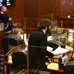 A page in the Alaska House of Representatives hands out copies of a budget bill over 100 pages long on Friday, April 30, 2021. (Peter Segall / Juneau Empire