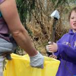 Delilah Whiteley, 7, a member of Girl Scout Troop 4009, grasps litter using a grabber tool and places it in a yellow litter bag held by Girl Scout Troop 4009 Troop Leader Sara Miller. (Ben Hohenstatt / Juneau Empire)
