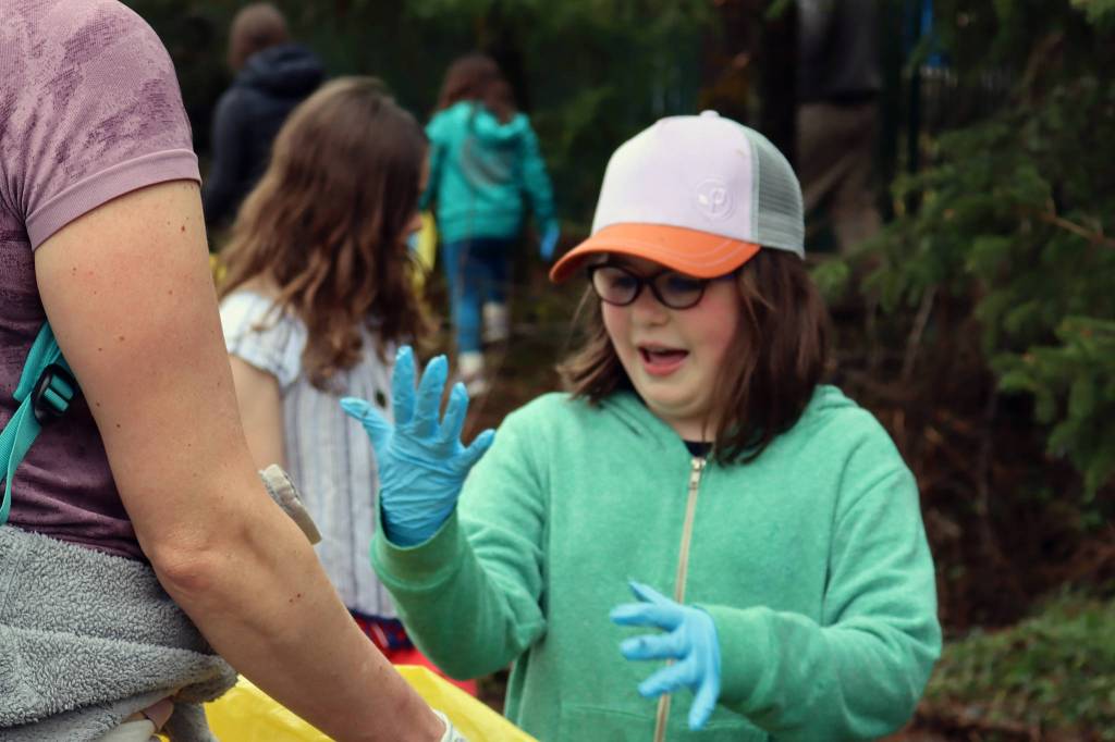 Nyah Harris, 8, a member of Girl Scout Troop 4009, reacts to the sensation of cold, slimy trash felt through the protective layer of her glove on Saturday, May 1, 2021. (Ben Hohenstatt / Juneau Empire)