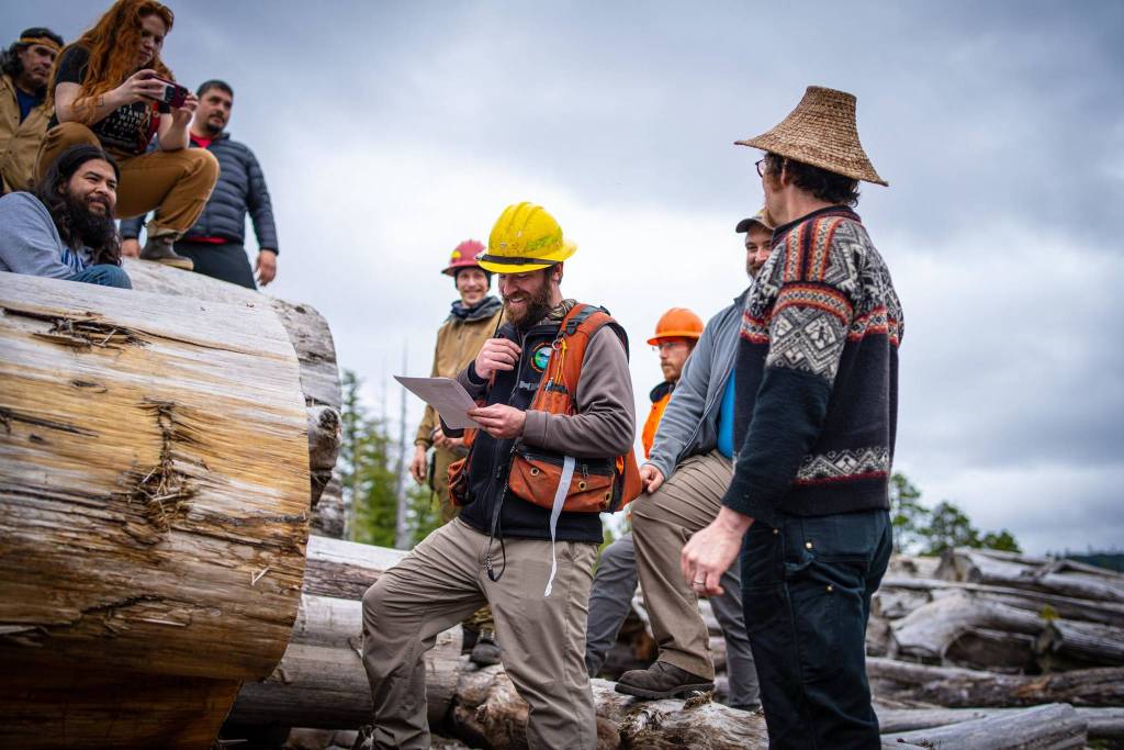 Justin Donnelley with the U.S. Forest Service references a document articulating the unique characteristics required for a dugout canoe, totem pole and bark-harvesting trees that tribal governments in Kasaan and Hydaburg produced based on feedback from artists and findings in a research paper. (Courtesy Photo / Bethany Sonsini Goodrich)