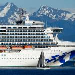 In this photo taken Wednesday, May 30, 2018, a sail boat maneuvers near a large cruise ship near Juneau, Alaska. On Monday night, members of the City and Borough of Juneaus Committee of the Whole considered whether to authorize city manager Rorie Watt to enter into port agreements that allow unvaccinated minors to visit Juneau with their families as long as certain conditions are met. (AP Photo/Becky Bohrer, file)