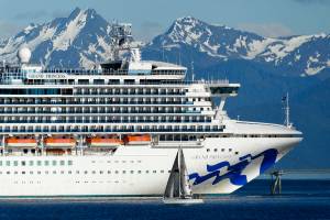In this photo taken Wednesday, May 30, 2018, a sail boat maneuvers near a large cruise ship near Juneau, Alaska. On Monday night, members of the City and Borough of Juneaus Committee of the Whole considered whether to authorize city manager Rorie Watt to enter into port agreements that allow unvaccinated minors to visit Juneau with their families as long as certain conditions are met. (AP Photo/Becky Bohrer, file)