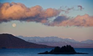 The full moon sets over Cohen Island, foreground, Shelter Island, left, and the Chilkat Mountain Range in this November 2013 photo. A fishing vessel sank Tuesday night near Shelter Island, according to the U.S. Coast Guard. People are advised to steer clear of the area of the sinking. (Michael Penn / Juneau Empire File)
